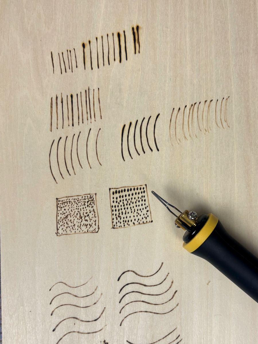 A woodburning practice board with rows of clean lines, curves, tapered flicks, and controlled shading tests